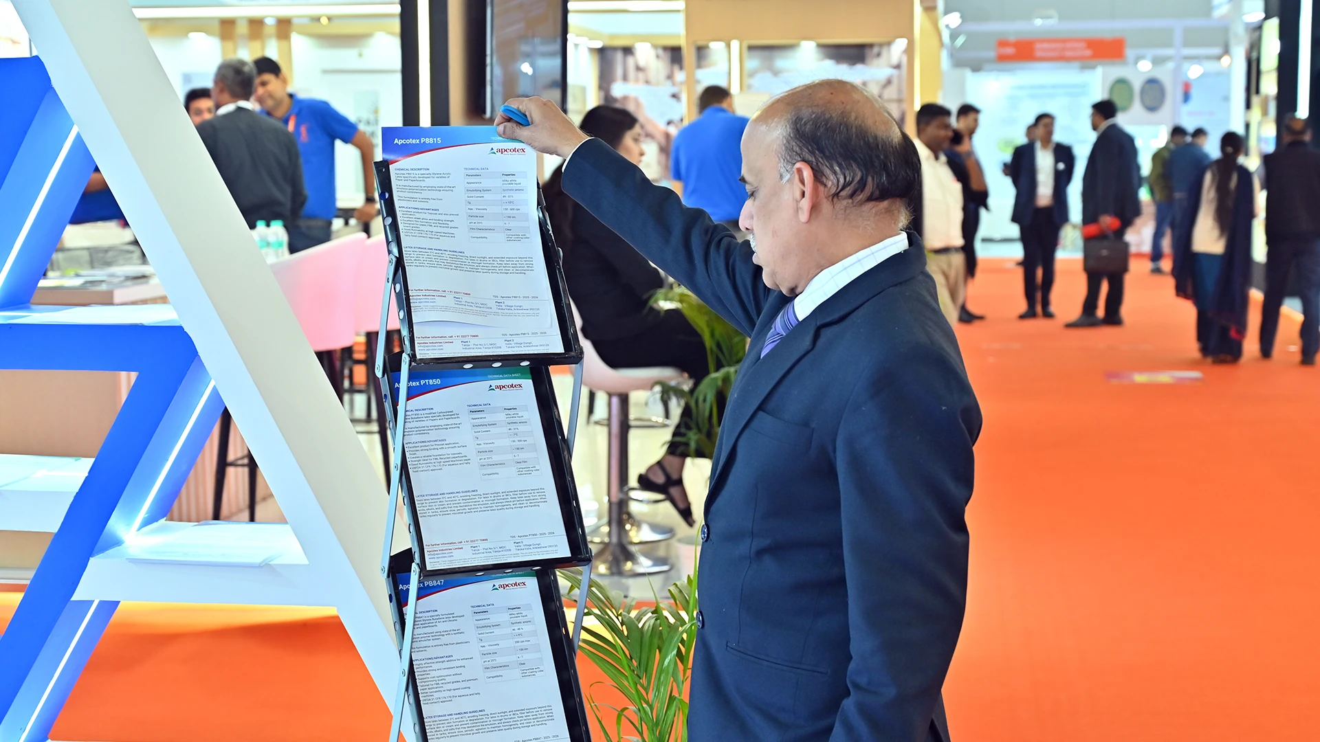 Visitor reviewing Apcotex technical data sheets at Paperex 2025, highlighting product-led B2B sales conversations at the exhibition stall.